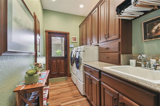 washroom with cabinet space, independent washer and dryer, light wood-type flooring, a sink, and recessed lighting