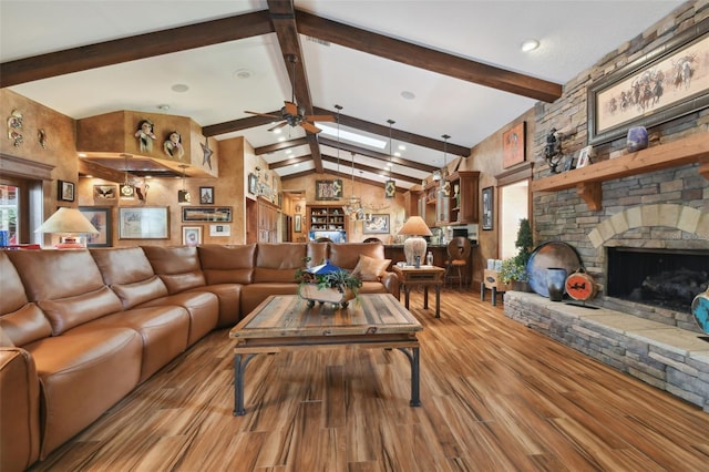 living room with lofted ceiling with beams, ceiling fan, a fireplace, and light wood-style floors