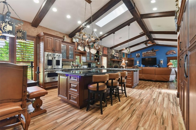 kitchen featuring a large island, glass insert cabinets, open floor plan, stainless steel double oven, and pendant lighting