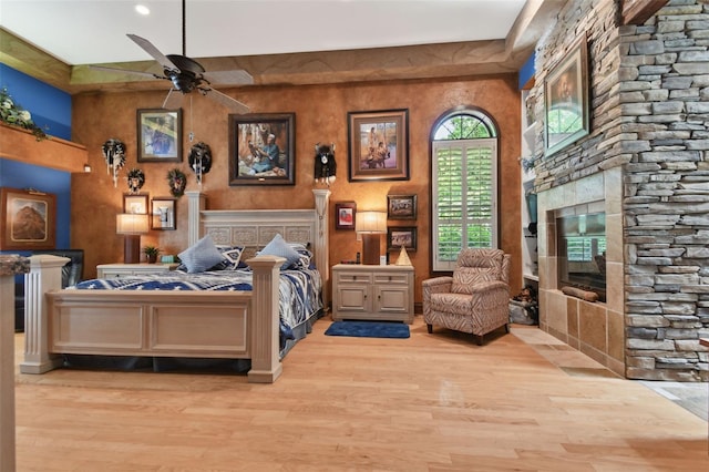 bedroom featuring a stone fireplace and light wood finished floors