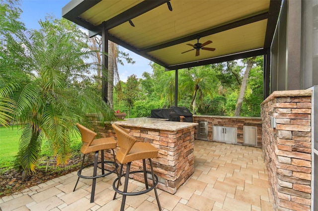 view of patio with exterior kitchen, ceiling fan, outdoor dry bar, and grilling area