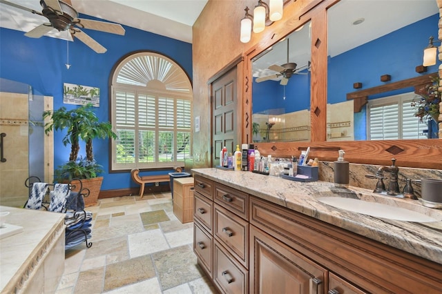 bathroom with stone tile floors, a ceiling fan, baseboards, vanity, and tiled shower