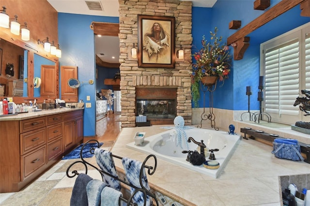 full bath with a whirlpool tub, an outdoor stone fireplace, vanity, and visible vents