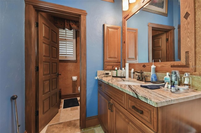 bathroom with toilet, vanity, and baseboards