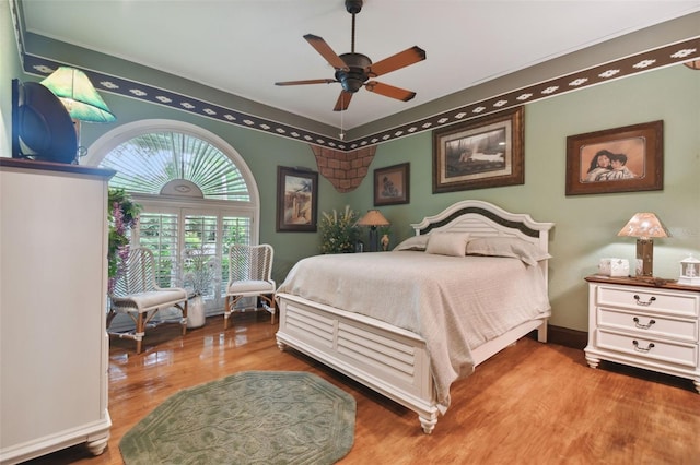 bedroom with wood finished floors, a ceiling fan, and baseboards