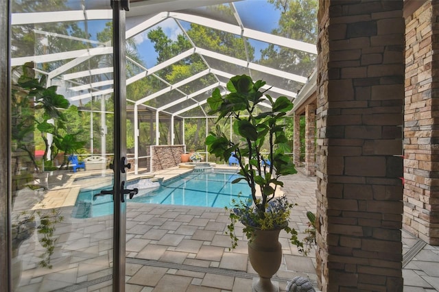 view of pool featuring glass enclosure, a pool with connected hot tub, and a patio