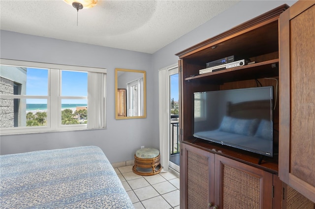 bedroom featuring ceiling fan, a textured ceiling, and light tile patterned floors