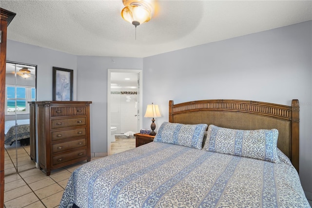 tiled bedroom with ensuite bath, ceiling fan, and a textured ceiling