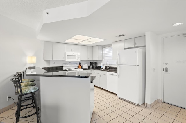 kitchen featuring white cabinetry, sink, white appliances, and kitchen peninsula