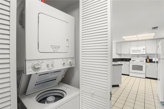 laundry room featuring stacked washing maching and dryer and light tile patterned floors