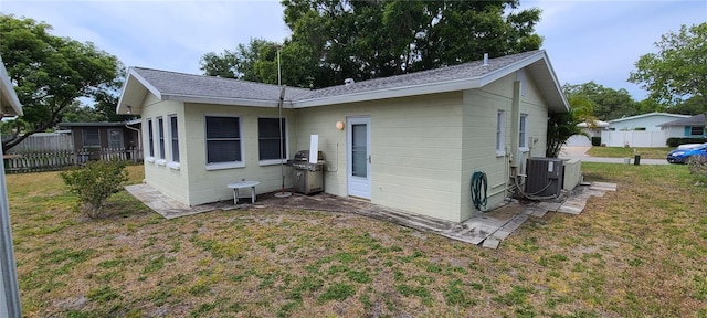 back of property featuring central AC unit and a lawn