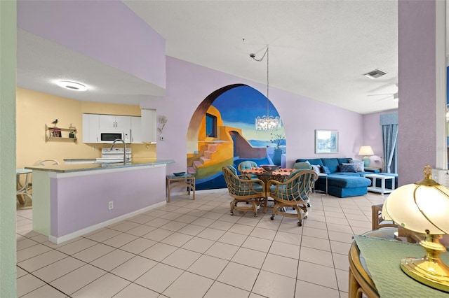 dining space with a textured ceiling, vaulted ceiling, and light tile flooring