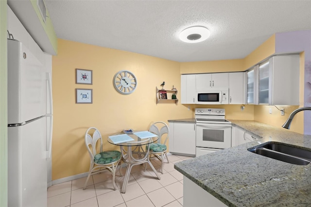 kitchen featuring white appliances, light stone countertops, light tile flooring, white cabinetry, and sink