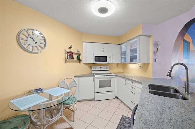 kitchen featuring white cabinetry, sink, white appliances, and light tile floors