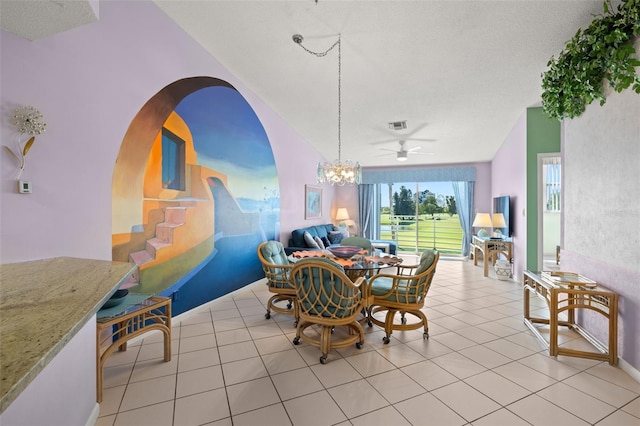 tiled dining room with ceiling fan with notable chandelier, a textured ceiling, and vaulted ceiling