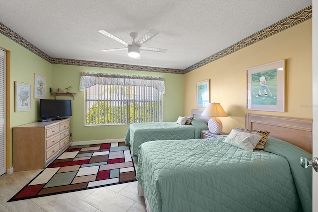 bedroom featuring a textured ceiling, ceiling fan, light tile floors, and multiple windows