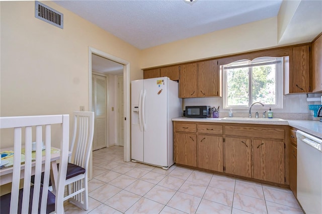 kitchen with backsplash, white appliances, sink, and light tile floors