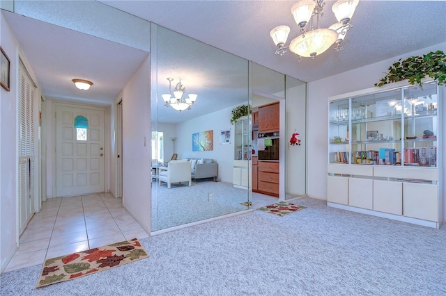 tiled foyer featuring a textured ceiling and a chandelier