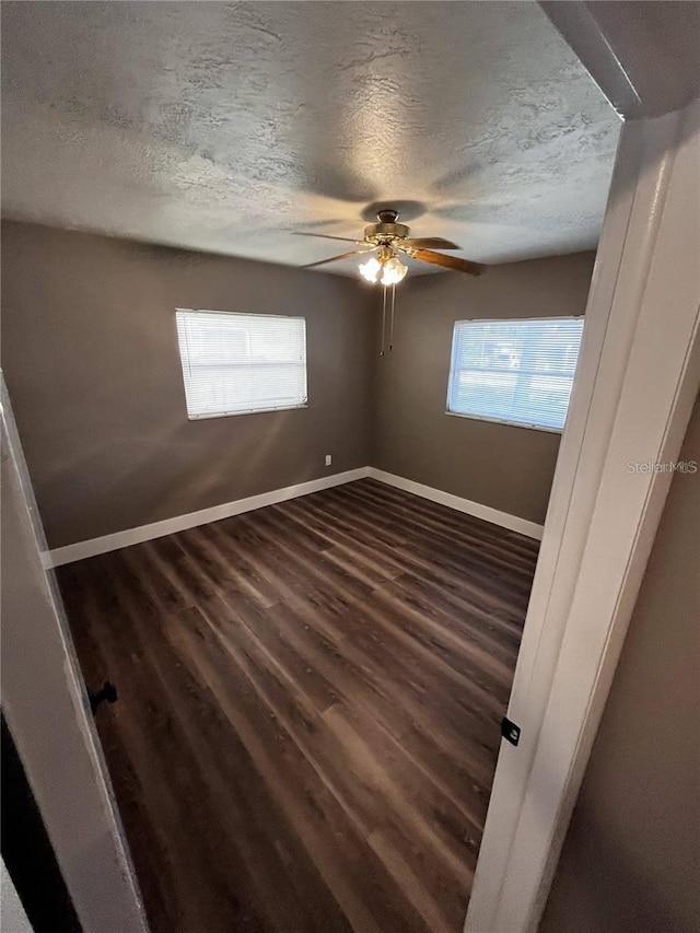 empty room featuring a textured ceiling, ceiling fan, and dark wood-type flooring