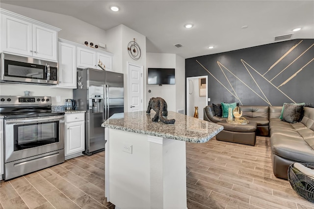 kitchen featuring white cabinets, light stone counters, light wood-type flooring, and stainless steel appliances