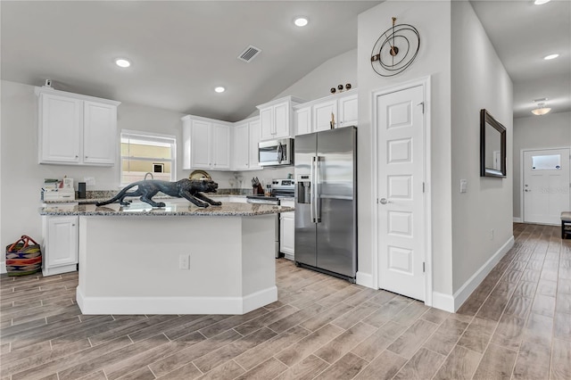 kitchen featuring appliances with stainless steel finishes, a kitchen island, vaulted ceiling, and white cabinets