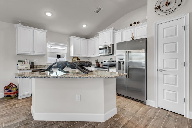 kitchen featuring white cabinets, lofted ceiling, an island with sink, and stainless steel appliances