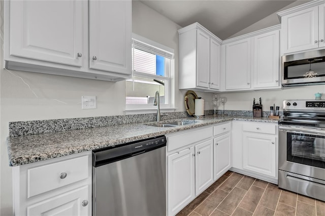 kitchen featuring vaulted ceiling, appliances with stainless steel finishes, white cabinets, and sink