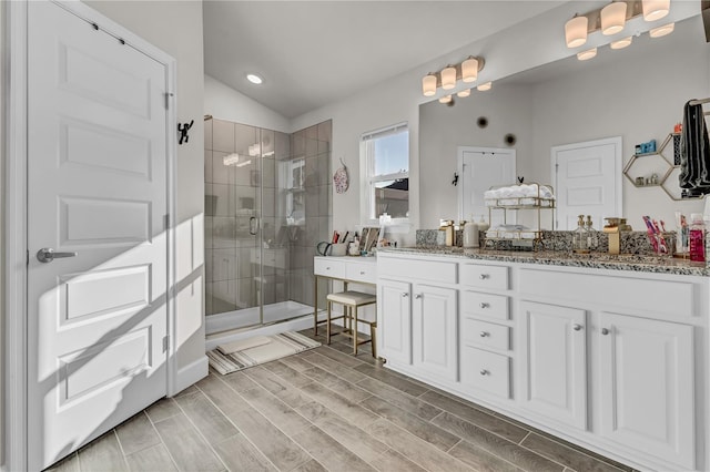 bathroom with an enclosed shower, vaulted ceiling, and dual vanity