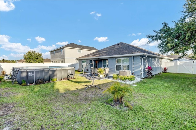 back of property with a fenced in pool, a yard, and central AC