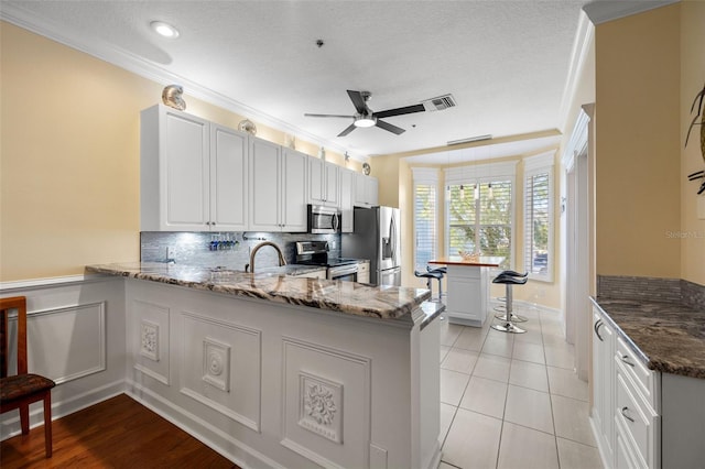 kitchen featuring backsplash, kitchen peninsula, white cabinetry, and stainless steel appliances