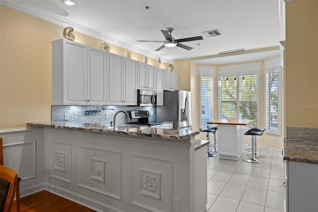 kitchen featuring stone counters, ceiling fan, stainless steel appliances, white cabinetry, and light tile floors