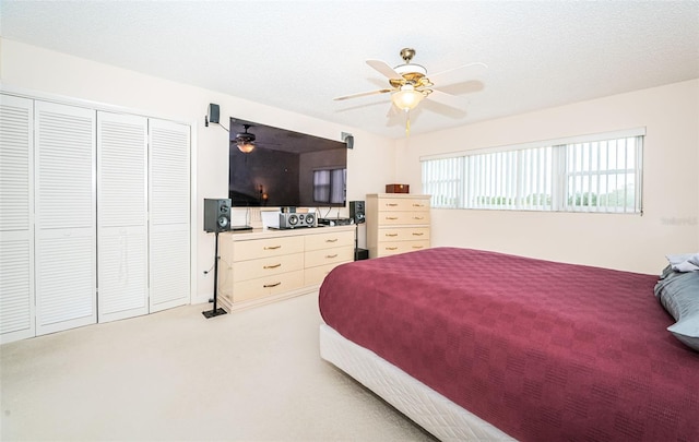 bedroom with ceiling fan, carpet floors, a closet, and a textured ceiling