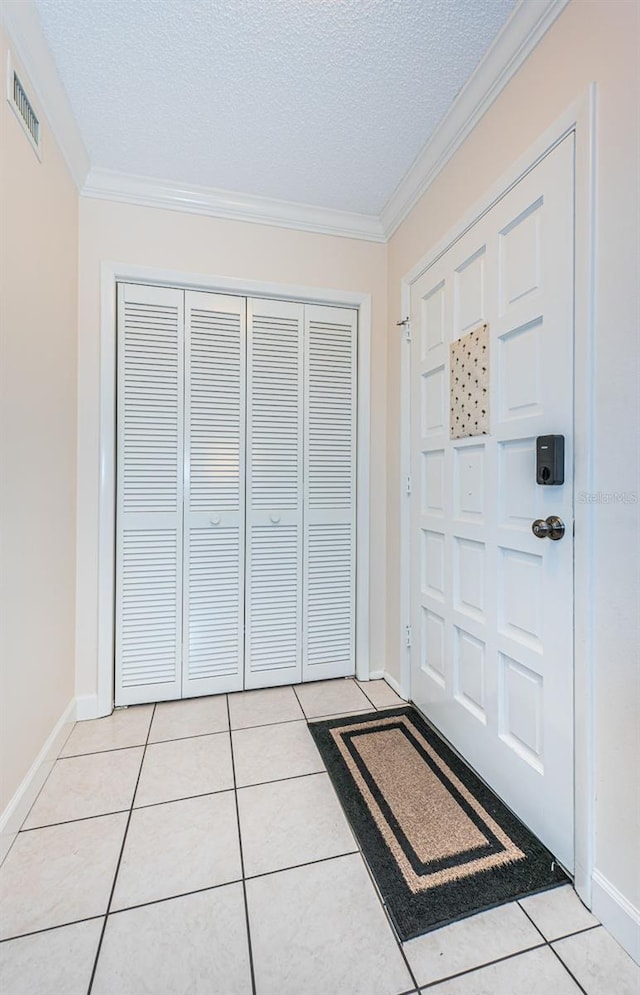 tiled entrance foyer featuring crown molding and a textured ceiling