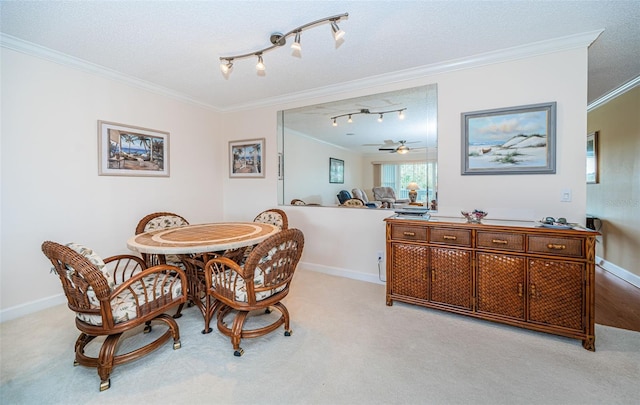 dining area with crown molding, rail lighting, ceiling fan, a textured ceiling, and light carpet