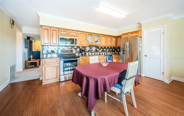 kitchen featuring appliances with stainless steel finishes, decorative backsplash, hardwood / wood-style flooring, crown molding, and a textured ceiling