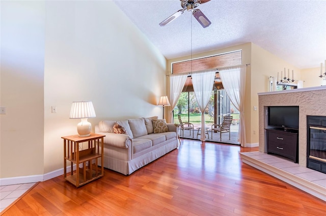 living room featuring a textured ceiling, wood-type flooring, a fireplace, and ceiling fan