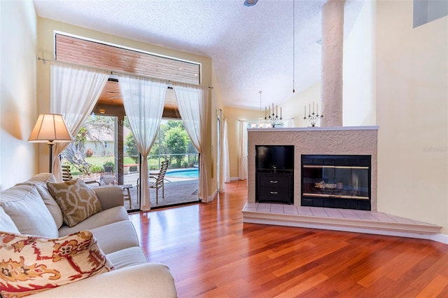 living room with a textured ceiling, a tile fireplace, and hardwood / wood-style floors