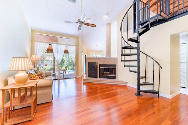 living room featuring hardwood / wood-style floors, a textured ceiling, a towering ceiling, and ceiling fan