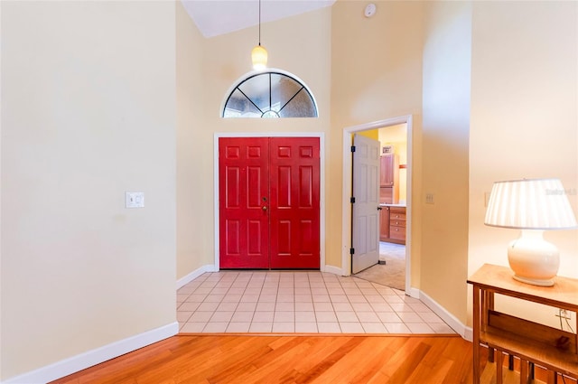 foyer with high vaulted ceiling and light wood-type flooring