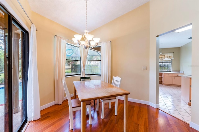 dining room with lofted ceiling, light hardwood / wood-style flooring, and an inviting chandelier