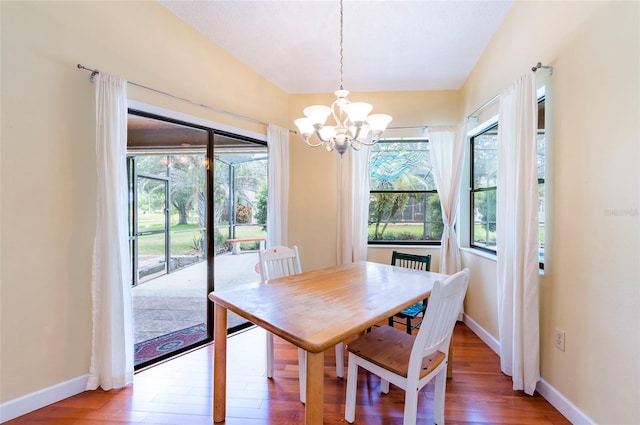 dining space with hardwood / wood-style flooring, a wealth of natural light, and a chandelier