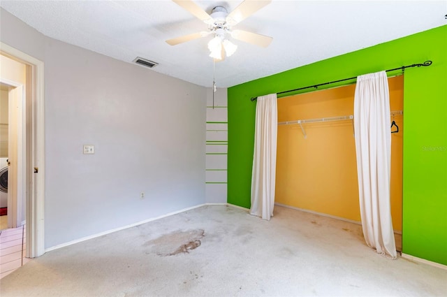 unfurnished bedroom featuring washer / dryer, a closet, light colored carpet, and ceiling fan