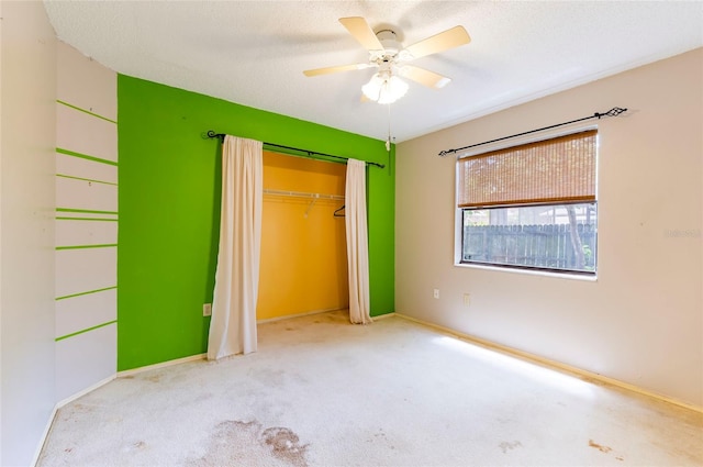 unfurnished bedroom with a closet, ceiling fan, light carpet, and a textured ceiling