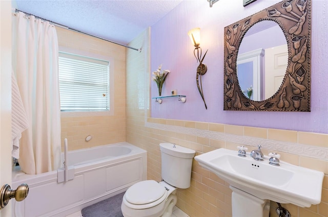 full bathroom with shower / tub combo, a textured ceiling, tile walls, toilet, and sink