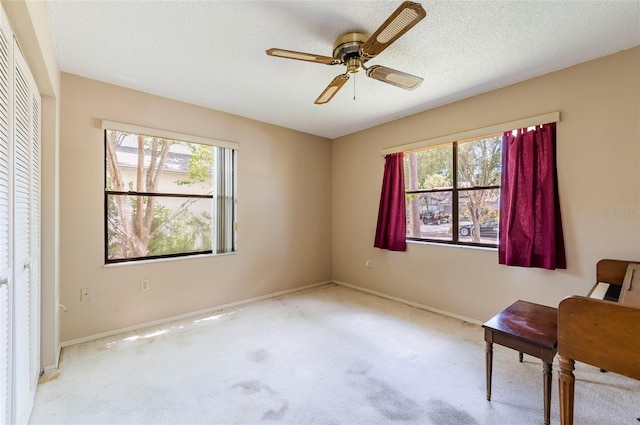 living area with light carpet, a textured ceiling, and ceiling fan