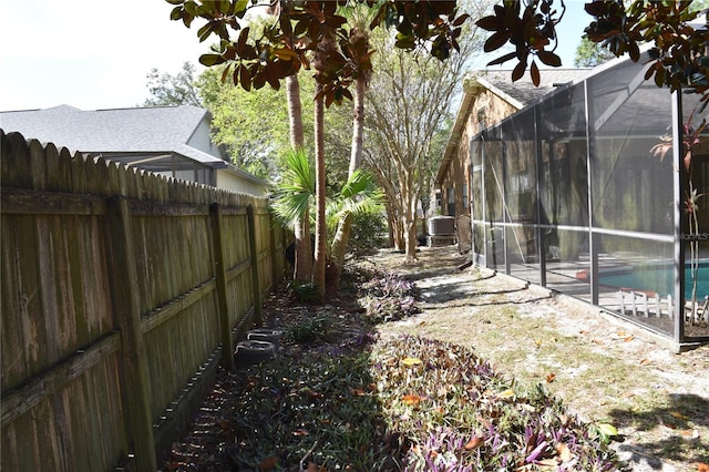 view of yard featuring a fenced in pool, cooling unit, and glass enclosure