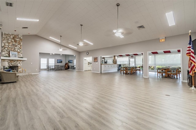 interior space featuring ceiling fan, a fireplace, a towering ceiling, and light hardwood / wood-style flooring