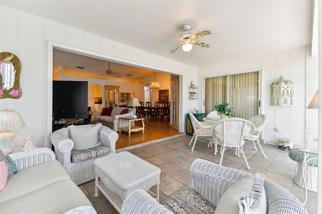 living room with tile patterned flooring and ceiling fan with notable chandelier