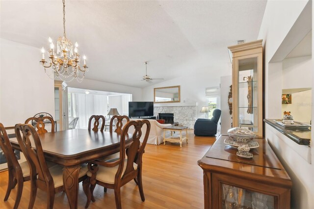 dining space with vaulted ceiling, ceiling fan with notable chandelier, and light hardwood / wood-style floors