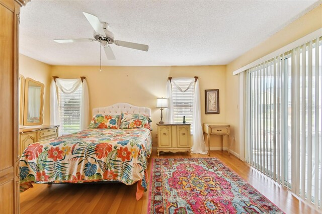 bedroom featuring ceiling fan, multiple windows, a textured ceiling, and light wood-type flooring